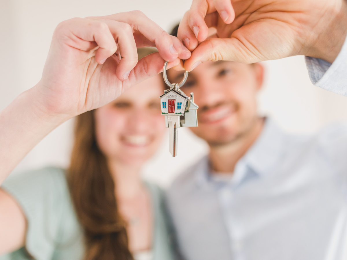 first-time homebuyers, A man and woman, holding up keys to their first home.