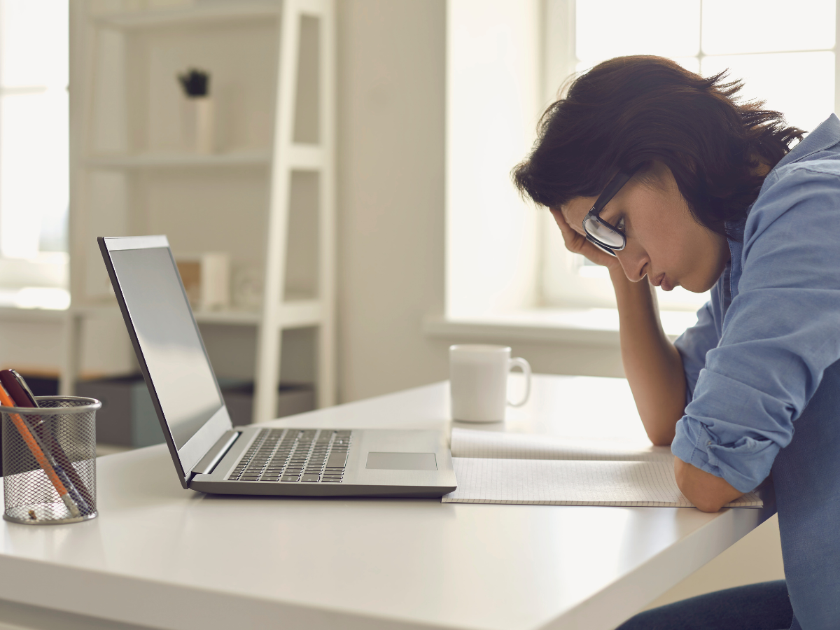 Exhausted Young Woman Working on A home sale mistake in Front of Laptop at Home Office